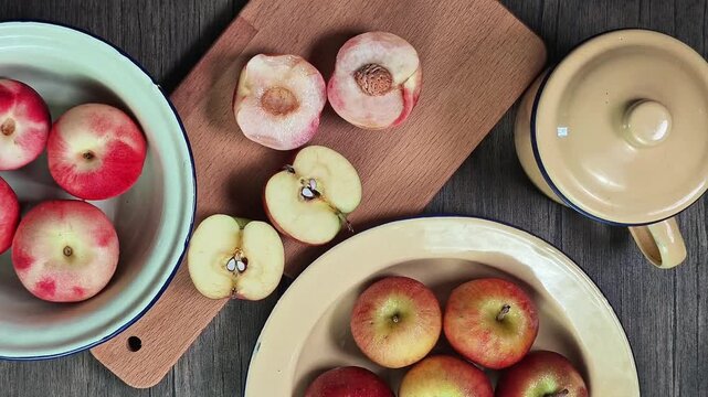 Red apple pink peach fruit whole sliced half seed tin plate chopping board wooded background