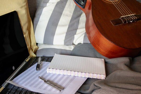 Creative process for songwriting and music composition with guitar, laptop, sheet music, and tuning fork, representing artistic work and productivity for musicians