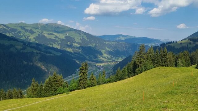 Scenic panorama of the Swiss Alps in summer, featuring rolling hills, lush green pastures under a sunny sky in a pristine alpine wilderness near Lenk, Simmental, Bern