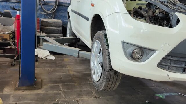 White Car Lifted on Hydraulic Service Hoist During Professional Automotive Maintenance