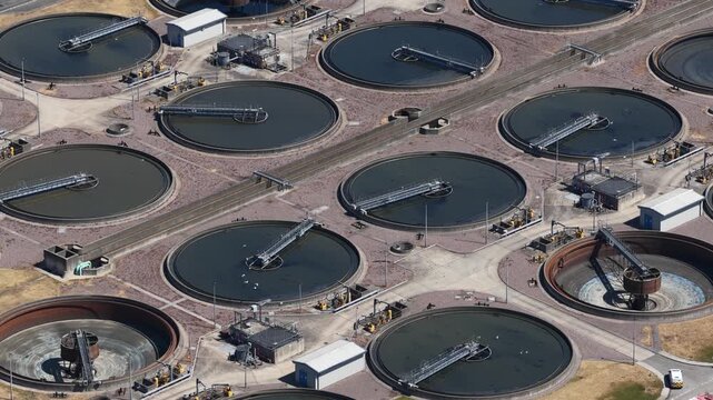 Aerial perspective showing the large circular clarifiers and sedimentation tanks of a modern wastewater treatment plant, purifying sewage and recycling water for the city's infrastructure