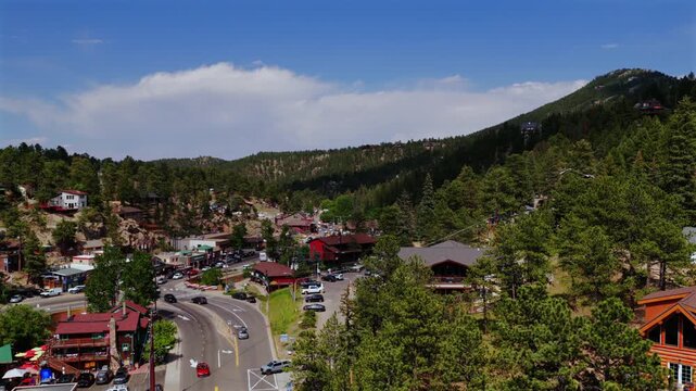 Cityscape highway 73 downtown Evergreen small mountain town aerial drone view main street business buildings Colorado cars Front Range Rocky Mountains summer spring sunny cloudy morning pan left