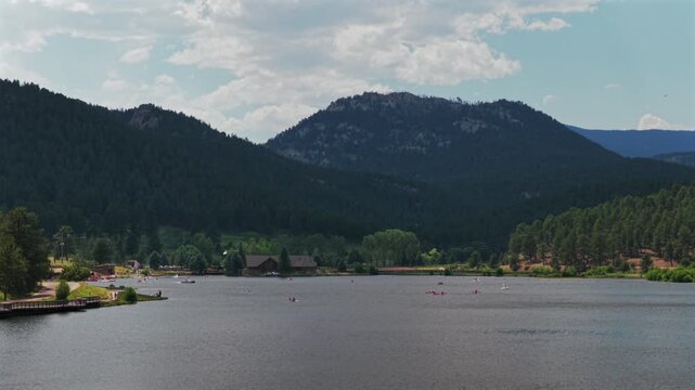 Spring Summertime Evergreen Lake nature landscape downtown Evergreen Colorado aerial drone pan left paddleboarders boats water sport activities hiking trails morning sunny clouds blue sky pan left