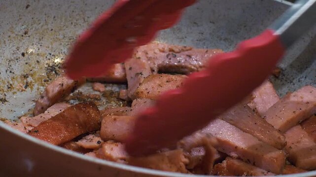 Stir frying seasoned spam over a skillet. Browning processed meat for a quick dinner recipe