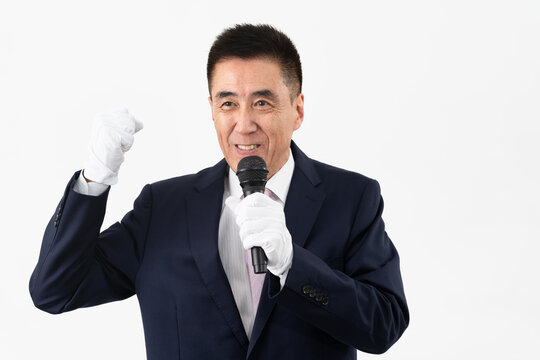 マイクを持ちながら選挙演説をするシニア男性