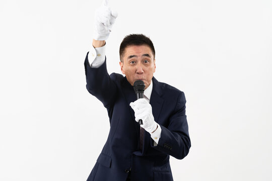 マイクを持ちながら選挙演説をするシニア男性