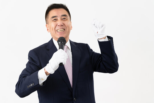 マイクを持ちながら選挙演説をするシニア男性