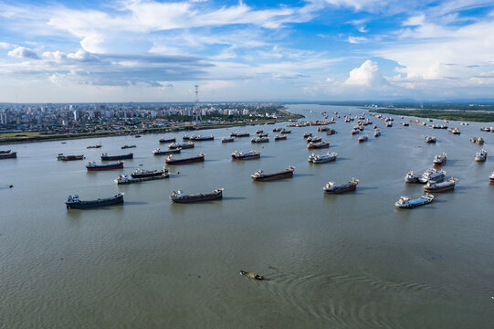 Chattogram, Chittagong Division, Bangladesh - 03 July 2026: Aerial view of numerous cargo ships anchored in the Karnaphuli River with the city skyline in the background.
