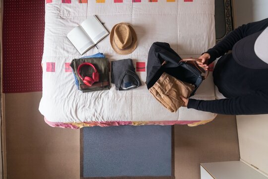 Top view of a man packing clothes into a bag to go on a trip