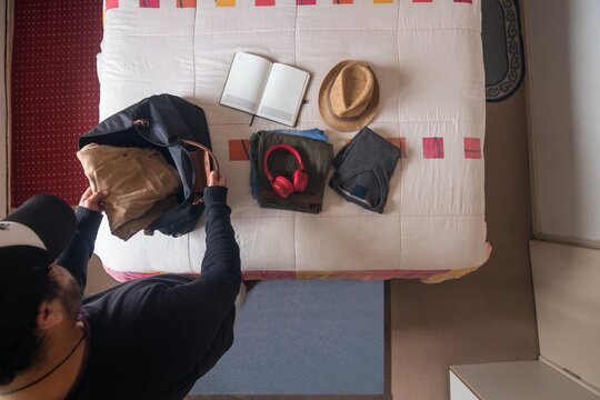 High-angle view of travel preparation with open notebook, folded clothes, and tote bag on bed