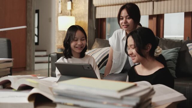 Three Asian teenage girls greeting in online class, remote learning at home using digital tablet, writing and reading textbooks, self-study for back to school, homeschooling education knowledge.