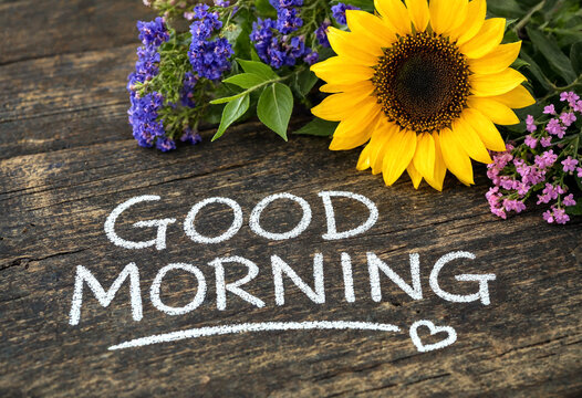 Bright sunflower and colorful flowers on rustic wooden background with good morning handwritten text