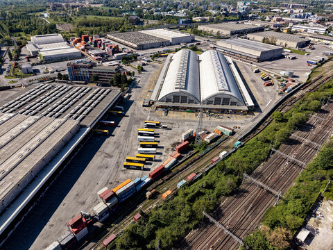Milan, Lombardy, Italy - 11 June 2026: Aerial view of the DSV logistics hub featuring large warehouses, rows of parked semi-trailers, and freight trains on adjacent tracks.