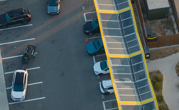 Villetelle, Occitanie, France - 18 July 2026: Aerial view of a Fastned solar-powered electric vehicle charging station with parked electric cars and a trailer.