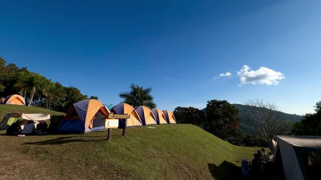 Panoramic view of colorful camping tents on a grassy hill at Doi Samer Dao in Sri Nan National Park, Nan, Thailand.