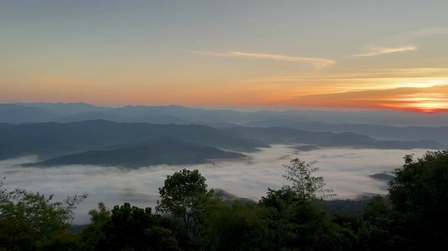 Bright golden sunrise breaking over a thick layer of morning mist and mountain ranges at Doi Samer Dao in Nan, Thailand.