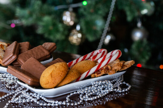 Plate of sweet food on table with Christmas decor candy canes tim-tams and ginger biscuits