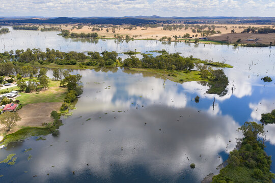 Aerial view of small islands and cloud reflections in a wide flooded inland river