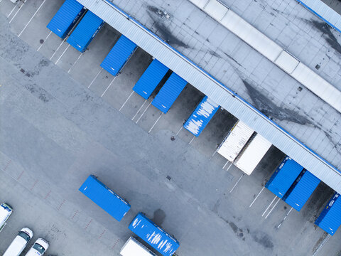 Skawina, Poland - 19 July 2026: Aerial view of the GLS sorting center, showing rows of blue shipping containers parked at the loading docks of a large industrial warehouse.
