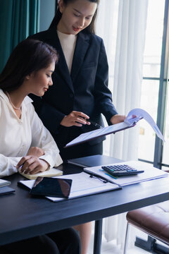 Asian boss businesswoman teaching intern work with document