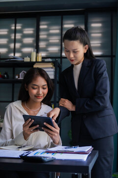 Asian boss businesswoman teaching intern working on tablet