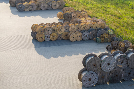 Krakow, Poland - 18 July 2026: Aerial view of numerous wooden cable reels stacked in an industrial yard at Tele-Fonika Kable S.A. in Krakow, Poland, with paved ground and grassy areas visible.