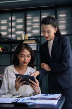 Asian boss businesswoman teaching intern working on tablet
