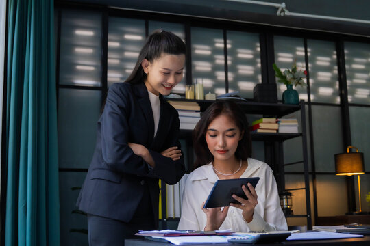 Asian boss businesswoman teaching intern working on tablet
