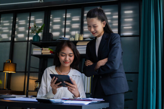 Asian boss businesswoman teaching intern working on tablet
