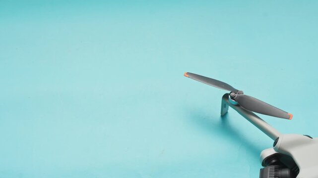 Extreme close-up of drone propeller spinning on cyan background with negative space
