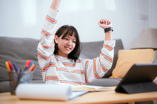 Young woman relaxing at home while studying on tablet during afternoon