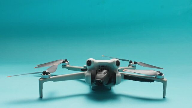Hand carefully landing modern mini drone on surface against cyan background
