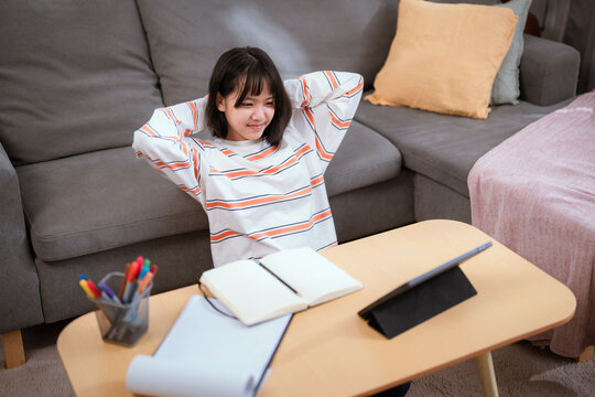 Young woman relaxing at home while studying on tablet during afternoon