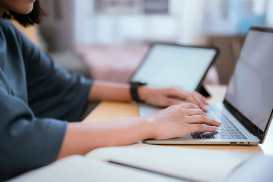 Young woman focuses on her laptop while working in a cozy living room during the day