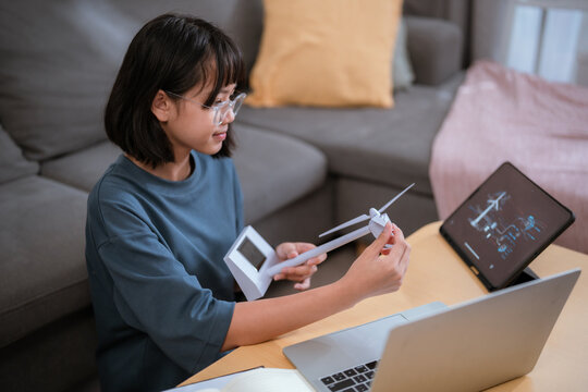 Young girl builds a model while sitting at a table in a cozy living room