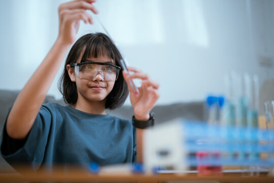 Young scientist conducting experiments at home with colorful liquids in glassware