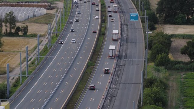 Weiterstadt, Germany - 27 July 2026: Aerial view of the e-highway test track with trucks and cars driving under overhead power lines on the autobahn.