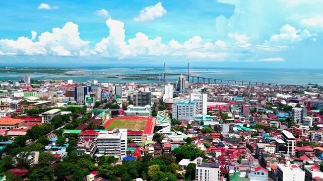 Cebu City, Philippines - 13 July 2026: Aerial view of the Cebu City skyline with dense urban buildings and the CCLEX bridge spanning the bay under a bright blue sky.