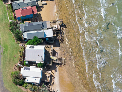 Aerial view of a row of houses along a sandy beach and gentle waves