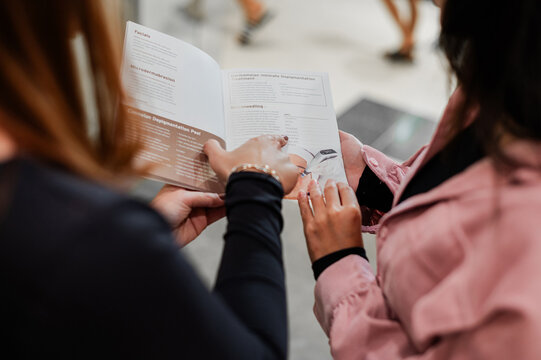 Beauty expert guiding a female client with their services using a brochure