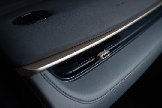 Close‑up of car interior detail highlighting dashboard air vent with metallic adjustment knob. Textured surface contrasts with smooth leather upholstery and visible stitching.