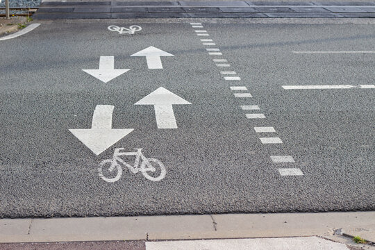 Road surface with painted directional arrows and bicycle lane markings indicating traffic flow for vehicles and cyclists in an urban area