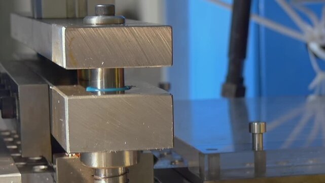 A precision hydraulic machine molds tiny blue parts in a sterile workshop during a high-quality afternoon production cycle.