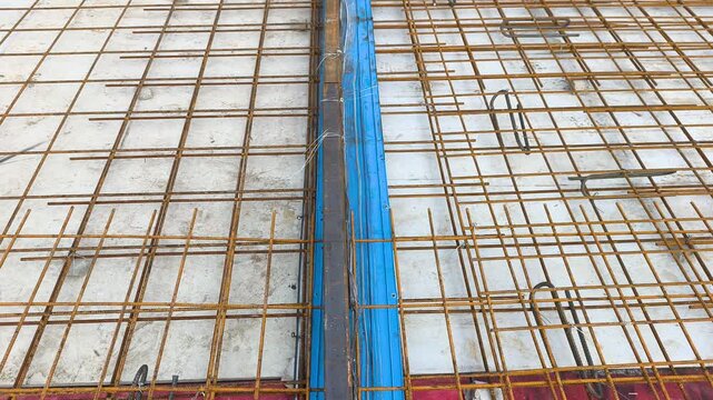 A blue rubber waterstop is installed along a concrete slab construction joint. It acts as a barrier to prevent water ingress through roof slab joints. The fitting ensures structural waterproofing.