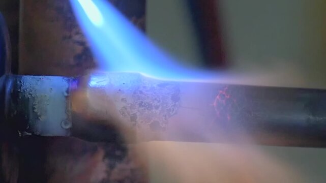 Molten metal flows into a glowing joint as a torch heats copper pipes during a precise afternoon plumbing repair.