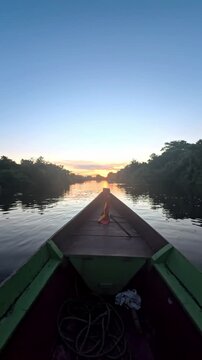 Rurrenabaque river boat journey at sunset with Bolivian flag navigating through the Amazon jungle