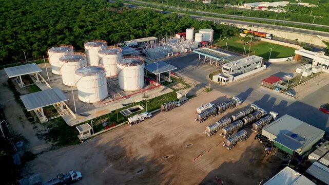 Merida, Yucatan, Mexico - 09 July 2026: Aerial view of petrochemical factory with large white storage tanks and tanker trucks parked in the facility yard.