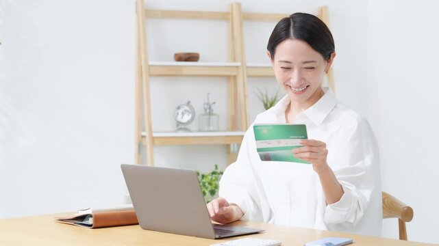 笑顔で預金通帳を見るミドル女性。貯金、銀行、投資、財テク、節約、マネー、お金、貯蓄、DX、家計、金融