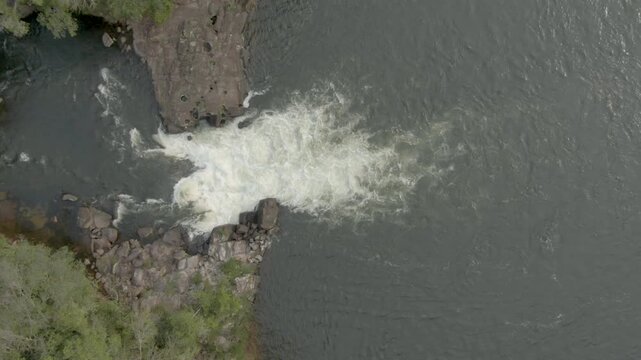 Aerial birdseye descending over rapids on sunny afternoon