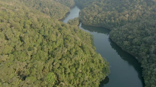 Winding River surrounded by lush vegetation at golden hour, Brazil. Aerial